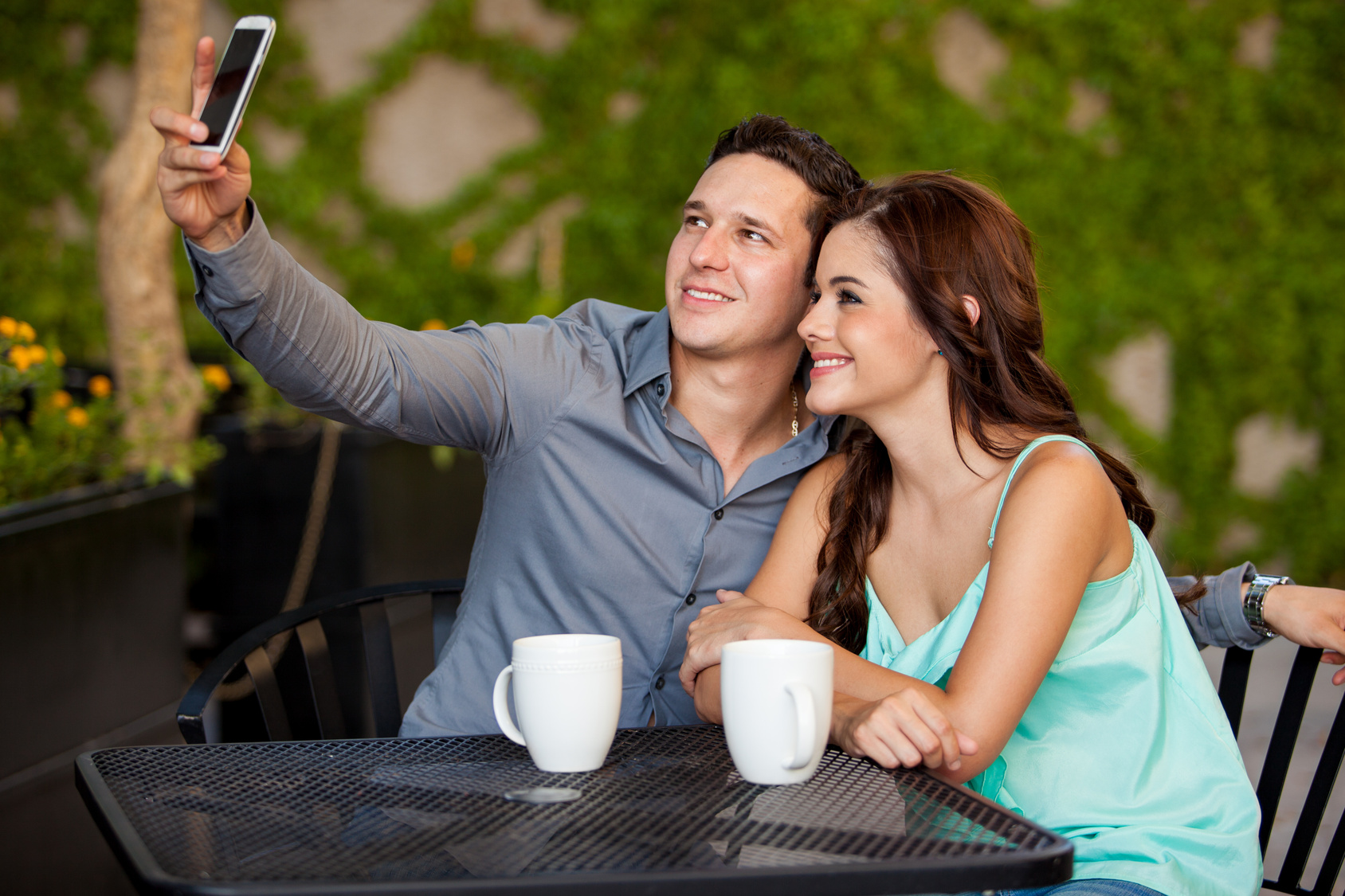 First date. Классное свидание. Девушка на веранде кафе. Мужчина фотографирует женщину. Мужчина романтично ухаживает за девушкой.